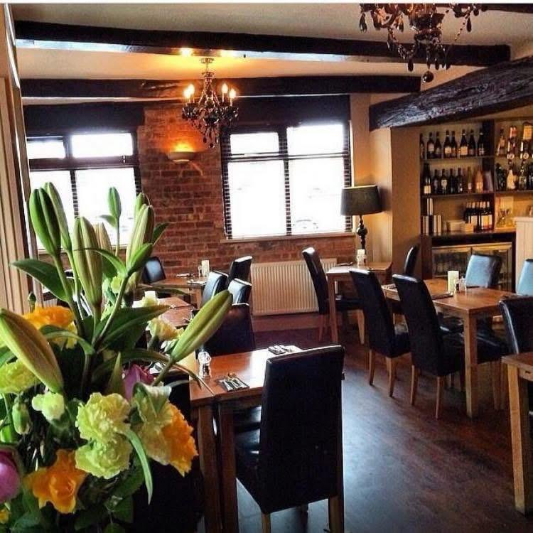 Fresh flowers on a table in the dining room, with the wine shelf and chandeliers behind
